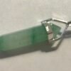 The Natural Serenity Aventurine Silver Pendant is a green, faceted, translucent crystal amulet with a silver cap and loop in minimalist style, pointed at both ends and shown on a white surface. The Natural Serenity Aventurine Silver Pendant is a green, faceted, translucent crystal amulet with a silver cap and loop in minimalist style, pointed at both ends and shown on a white surface.